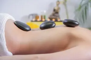 a massage therapist is performing hotstone treatment